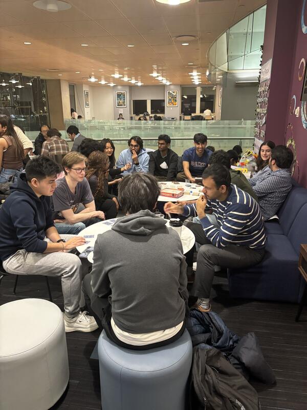 Students gathered around round white tables, playing board games.