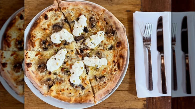 aerial shot of a white truffle, ricotta, and mushroom pizza on a wooden table