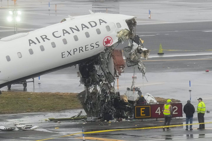 Officials investigate the site, Monday, March 23, 2026, where an Air Canada jet came to rest after colliding with a Port Authority firetruck at LaGuardia Airport, shortly after landing Sunday night in New York.