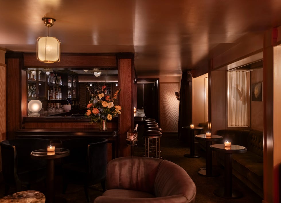 A cozy, dimly lit bar setting with seating and floral decor. A cozy, dimly lit bar setting with seating and floral decor.