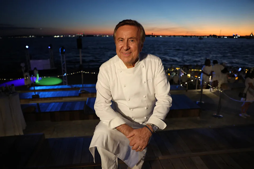 A chef posing on a balcony outside at night.