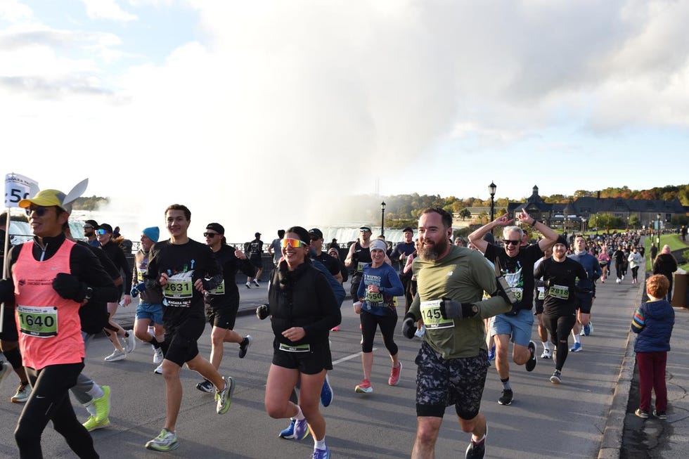 Participants running in a race with a waterfall in the background. Niagra Falls International Marathon