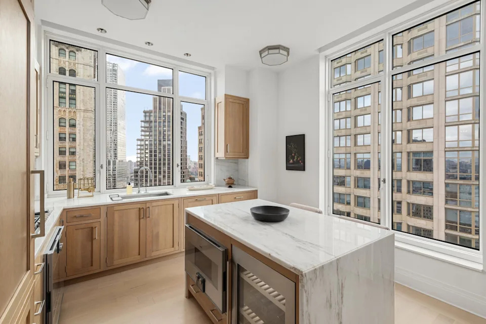 A kitchen with wooden cabinets and views of New York City in the Four Season Duplex in Manhattan New York