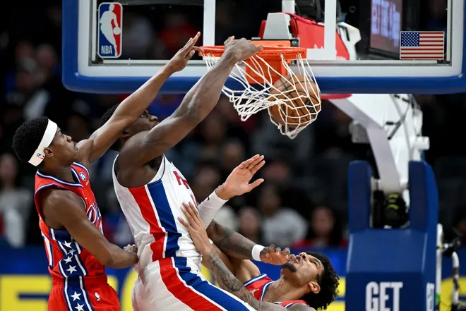 Mar 12, 2026; Detroit, Michigan, USA; Detroit Pistons center Jalen Duren (0) dunks the ball between Philadelphia 76ers defenders VJ Edgecombe (left) and Dominick Barlow in the second half at Little Caesars Arena.