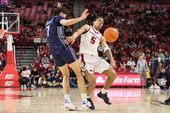 Arkansas Razorbacks guard Darius Acuff Jr is fouled by Queens Royals forward Gus Larson.