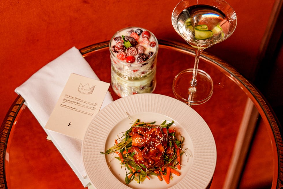A table setting featuring a plate of food, a drink, dessert, and a menu.