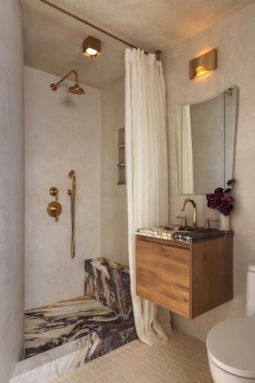 Modern bathroom featuring a shower with gold fixtures, a wooden vanity with a marble top, and a white curtain.