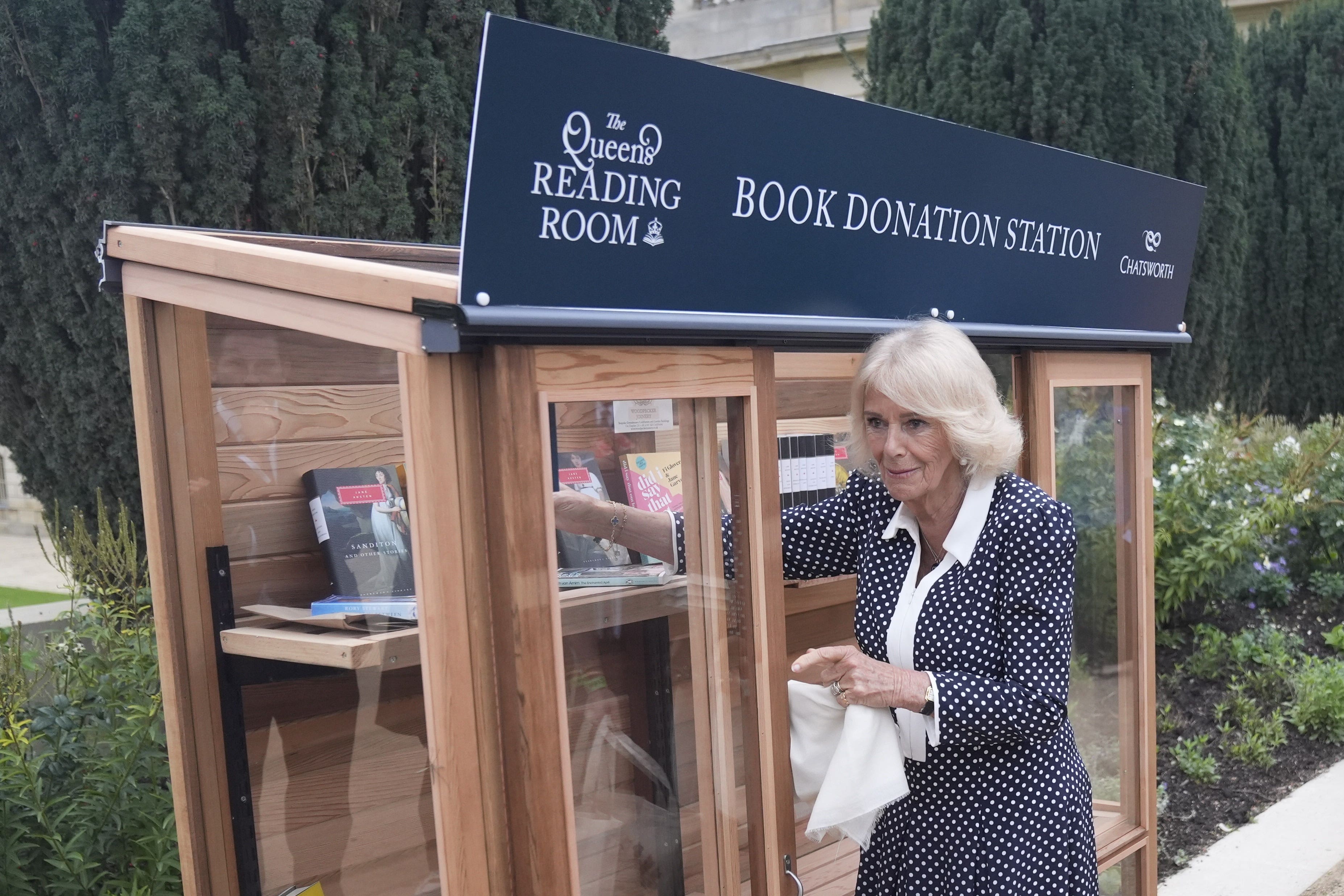 Queen Camilla places books in a donation point for The Queen’s Reading Room