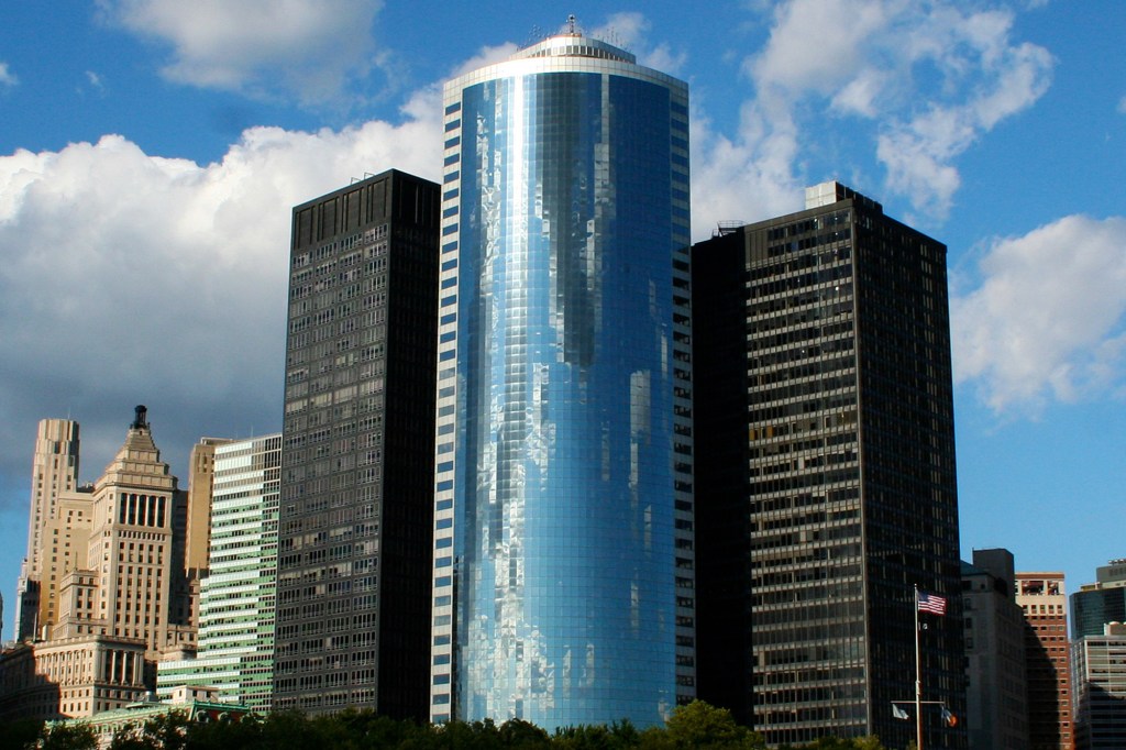 The curved glass skyscraper of 17 State Street, Manhattan, New York, USA, reflecting the sky.