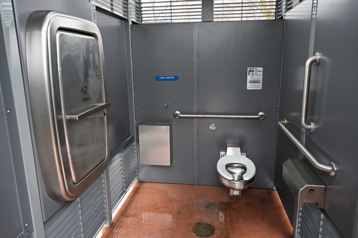 Inside the Irving Square restroom in Brooklyn. The stainless-steel bathroom includes a toilet, hand sanitizer, baby changing station, and slatted openings for ventilation and safety.