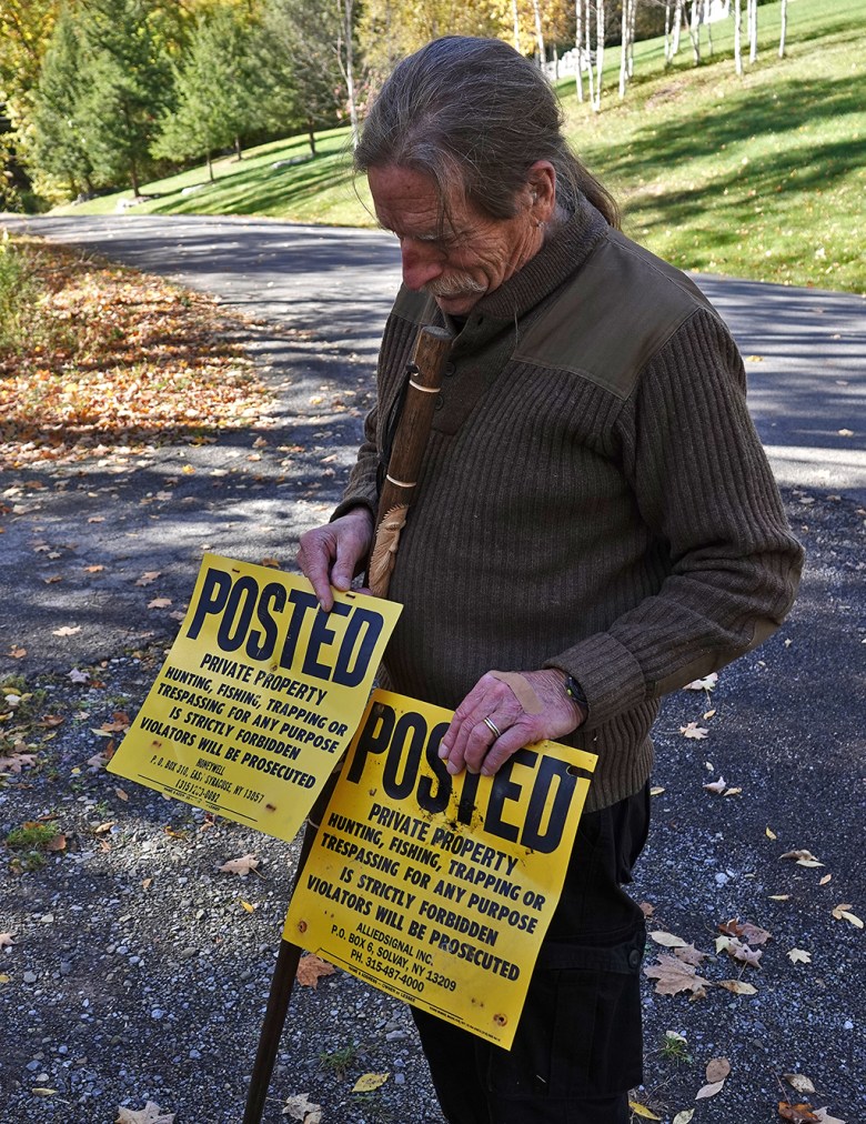 Joe Heath holds posted signs he took down on the 1,000 acres of land returned to the Onondaga Nation.