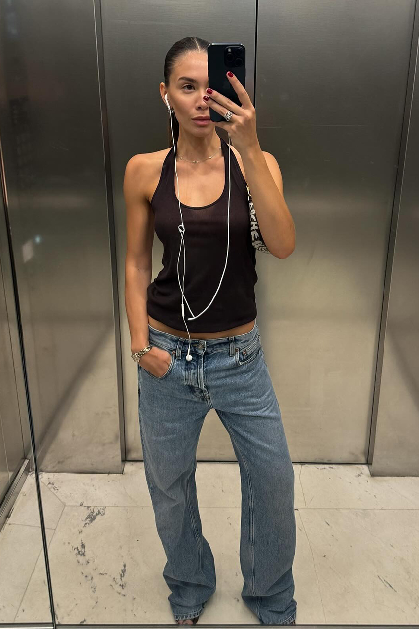 a woman wearing a black tank top and blue jeans
