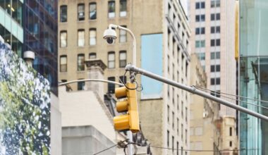 Security camera and traffic light are mounted on a pole, keeping watch over a bustling city street in New York City.