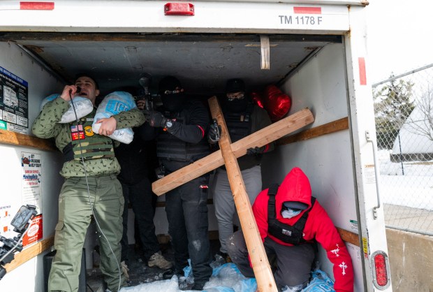 Right wing influencer Jake Lang (L) rides in the back of a U-Haul truck as it drives by a demonstration outside the Bishop Henry Whipple Federal Building on Feb. 7, 2026 in Minneapolis, Minnesota. (Photo by Stephen Maturen/Getty Images)