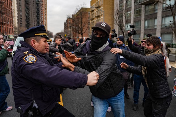 An NYPD officer grabs a left-wing activist for trying to block a vehicle carrying right-wing influencer Jake Lang on Saturday, March 7, 2026 in New York City. (Photo by Ryan Murphy/Getty Images)