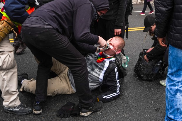 A left-wing activist's eyes are flushed with water after being pepper sprayed by a right-wing demonstrator at a protest organized by right-wing influencer Jake Lang on March 7, 2026 in New York City. (Photo by Ryan Murphy/Getty Images)