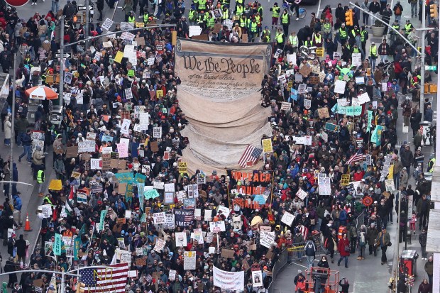 Protesters holding a large sign depicting the Declaration of Independence march near Times Square during the "No Kings" national day of protest in New York on March 28, 2026. (Photo by CHARLY TRIBALLEAU / AFP via Getty Images)