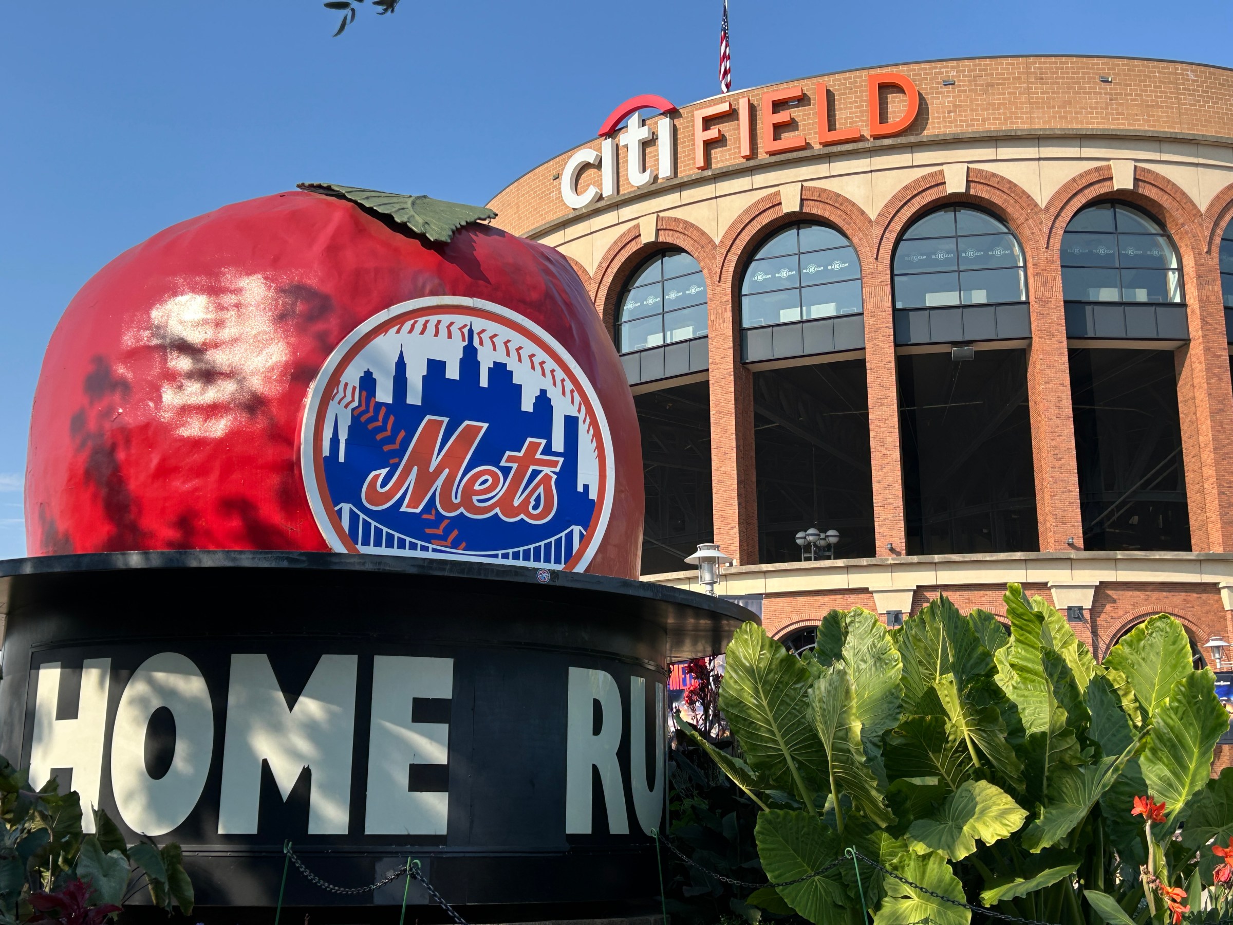 A red apple statue outside of a brick baseball stadium.