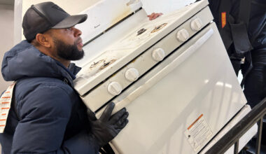 Workers remove an old stove from a Bronx apartment as part of a full-building induction stove installation in New York City. Credit: Lauren Dalban/Inside Climate News