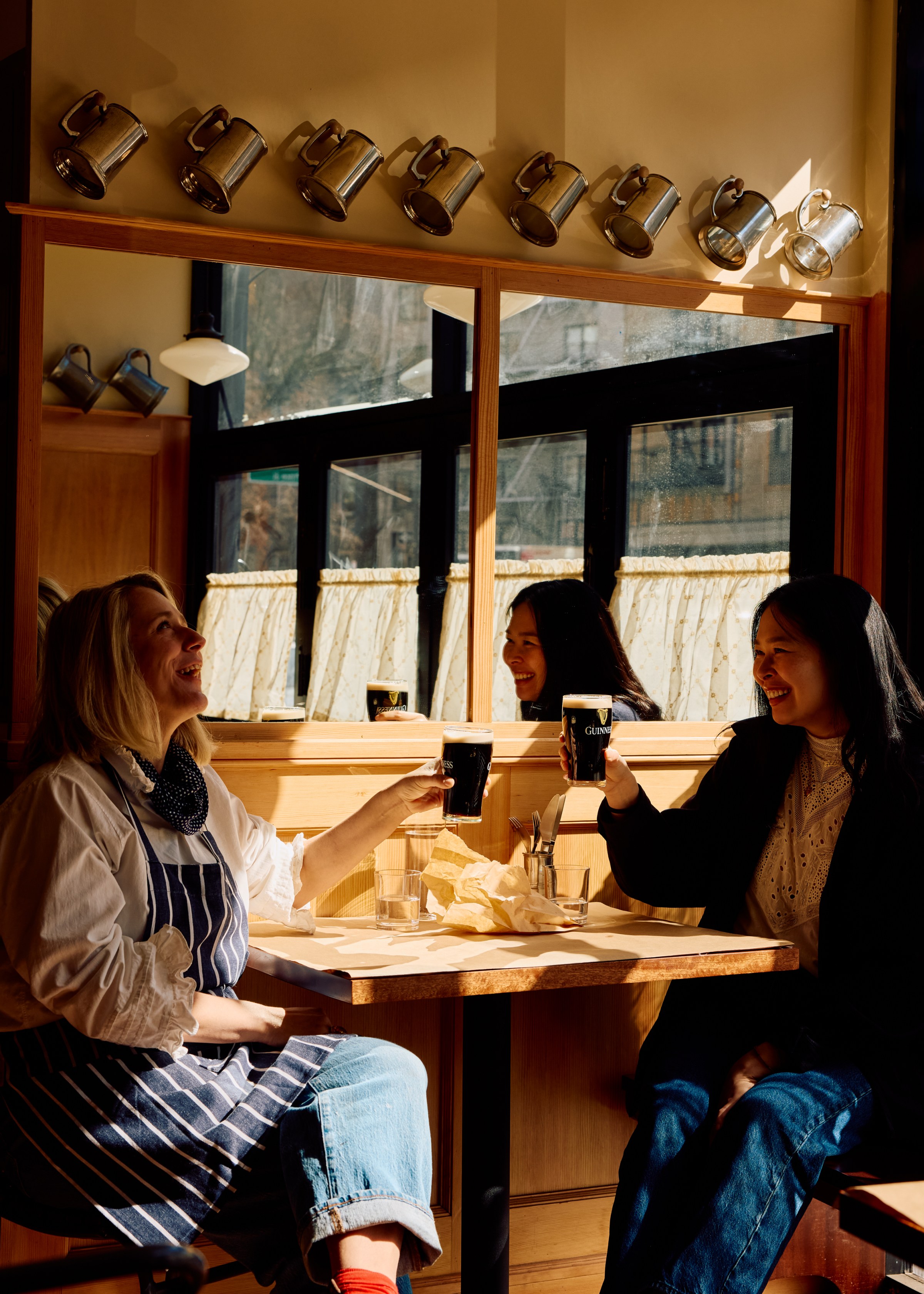 Two people cheersing with beer in a restaurant.