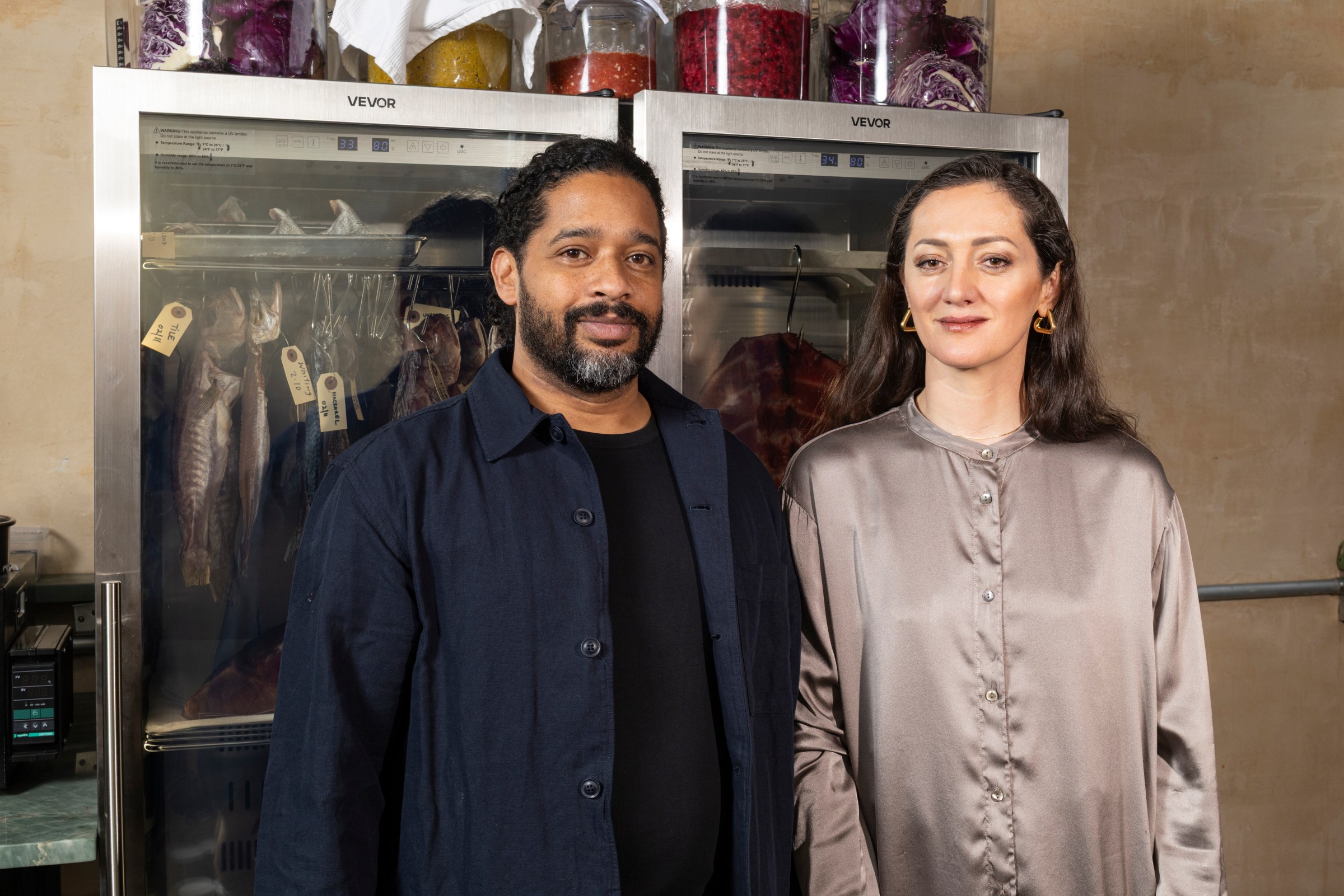 Two people standing in front of a clear freezer.