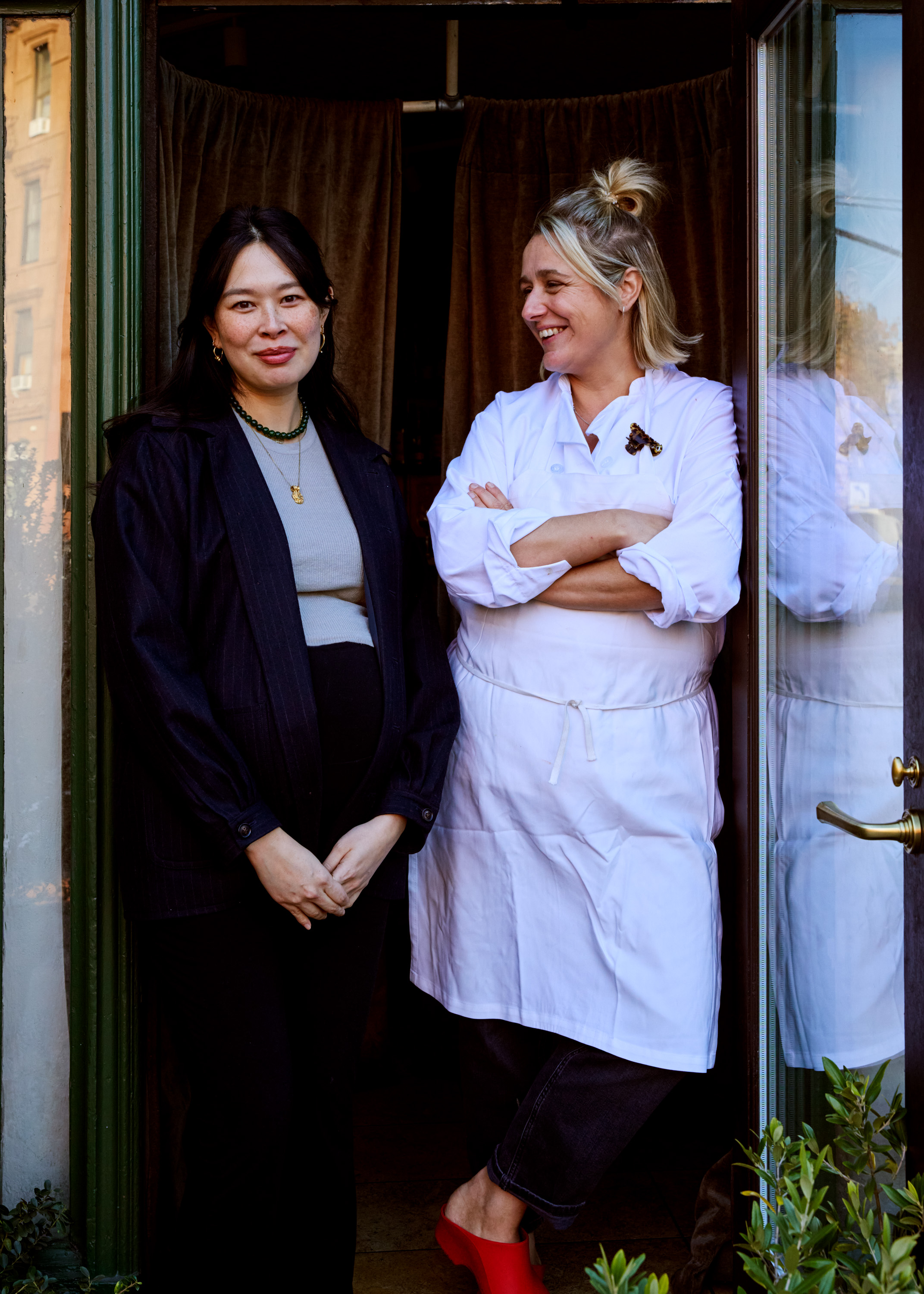 Two people standing at a restaurant door.