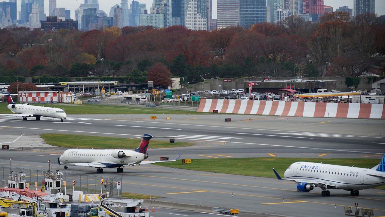 FILE - The New York City skyline is seen behind planes waiting to take off at LaGuardia Airport in New York, Nov. 22, 2023. Most Americans believe that air travel is generally safe in the U.S., despite some doubts about whether aircraft are being properly maintained and remain free from structural problems.(AP Photo/Seth Wenig, File)