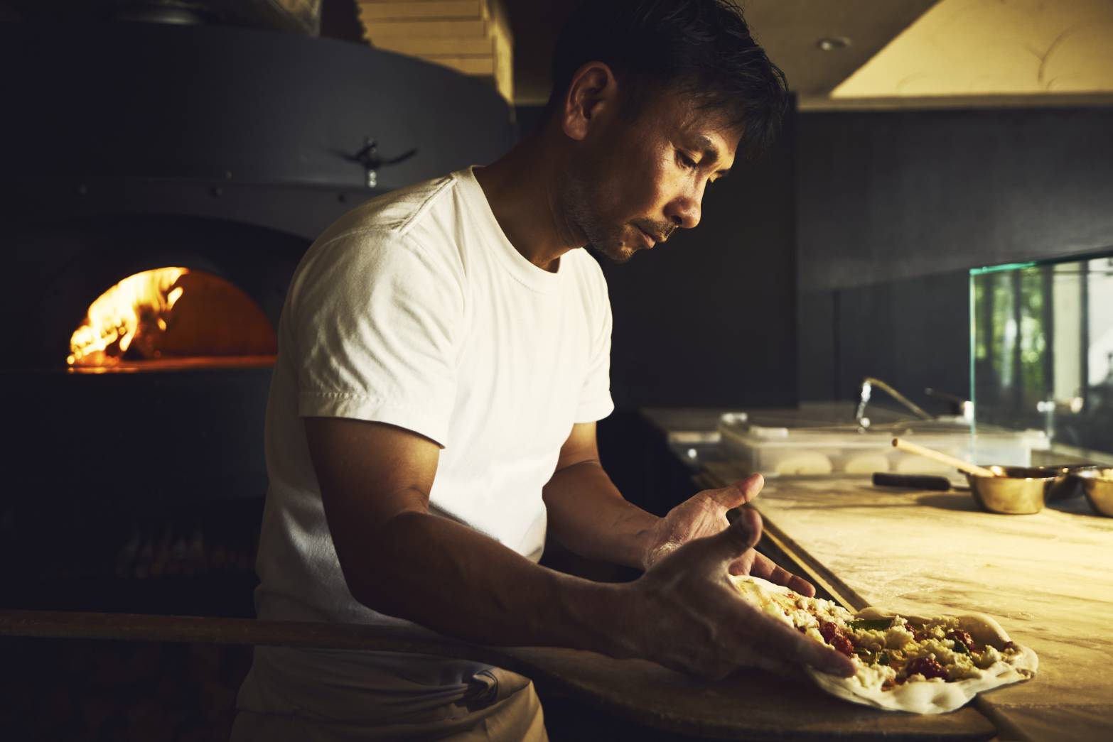 A person making a pizza dough in a kitchen.