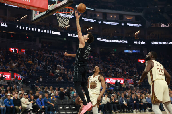Brooklyn Nets guard Ben Saraf (77) shoots against Golden State Warriors guard De'anthony Melton (8) during the first half of an NBA basketball game in San Francisco, Wednesday, March 25, 2026. (AP Photo/Jed Jacobsohn)