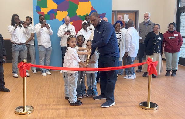 man surrounded by children getting ready to cut a ribbon at christina's child care center in brooklyn park