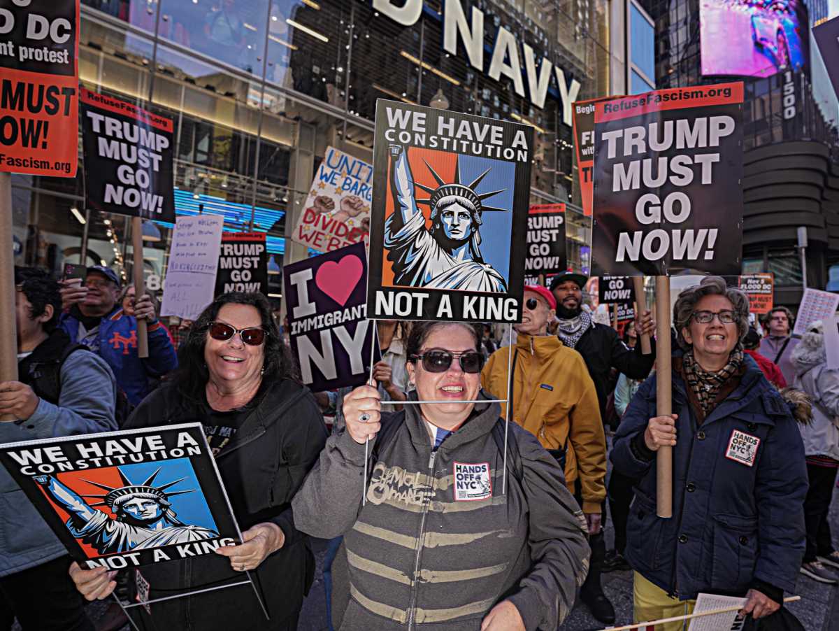 people hold signs at no kings protest