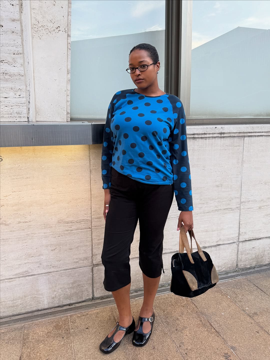 Woman wearing a black capris and a blue polka-dot top.