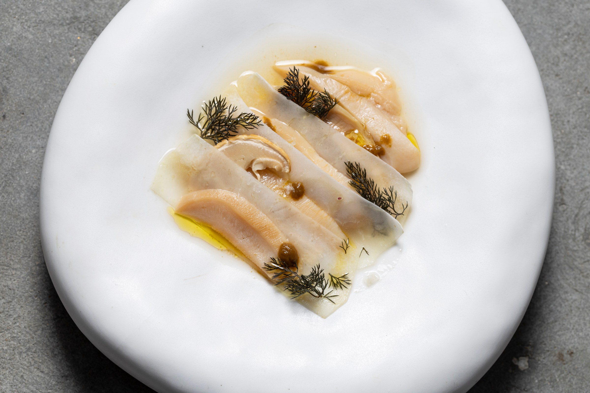 A plate of thinly sliced fish in a yellow borth.