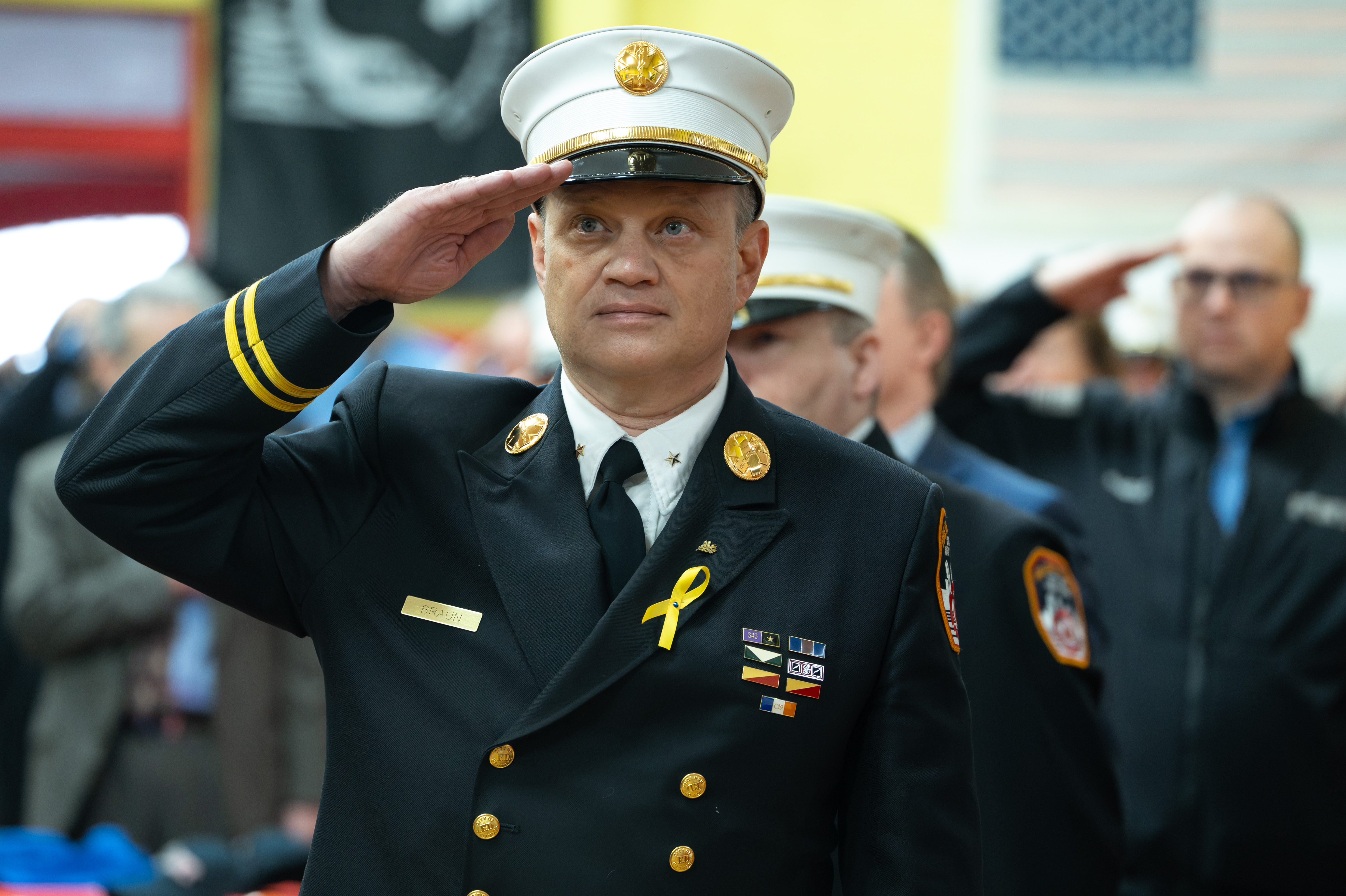 A FDNY members salutes the U.S. and other flags during a ceremony commemorating the 30th anniversary of the merger of NYC Health and Hospitals EMS with FDNY at the FDNY EMS Bureau of Training in Ft. Totten Park on Monday, March 16, 2026 in Queens, New York. (Barry Williams/ New York Daily News)