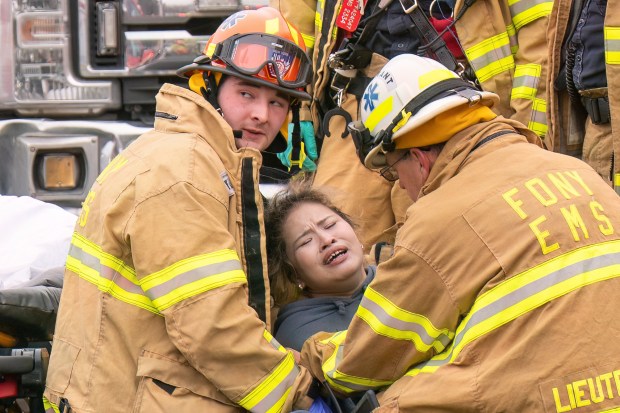 (The woman seen here could be heard shouting in anguish "No, my baby, my baby, I want to see my baby" followed by repeats of "I want to see my baby". She then hopped off the gurney and fought with Medics to get away, whereupon she headed back to the fire scene before being intercepted by Medics, with several Medics eventually needed to hold her down) Three people were killed, including a child of unknown age, with several others suffering serious injuries, after a four-alarm fire broke out inside a two story residence at 44-49 College Point Boulevard in Queens on Monday March 16, 2026. 1309. (Theodore Parisienne / New York Daily News)