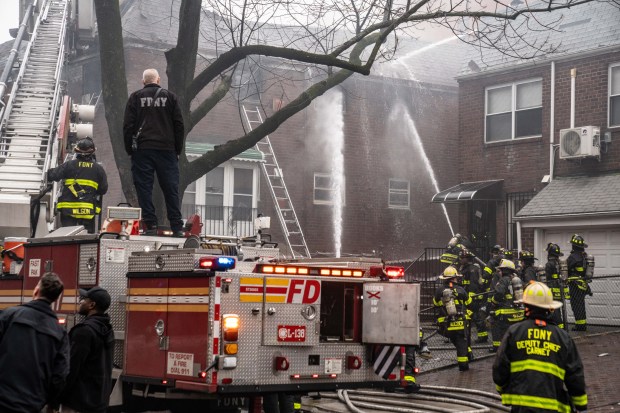 Firefighters battle a four-alarm fire on College Point Boulevard in Queens on Monday.