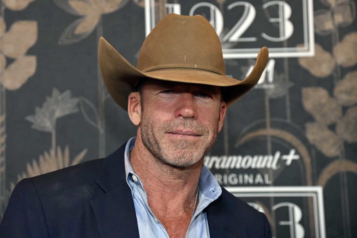 Taylor Sheridan wears brown cowboy hat in front of press step and repeat for paramount plus