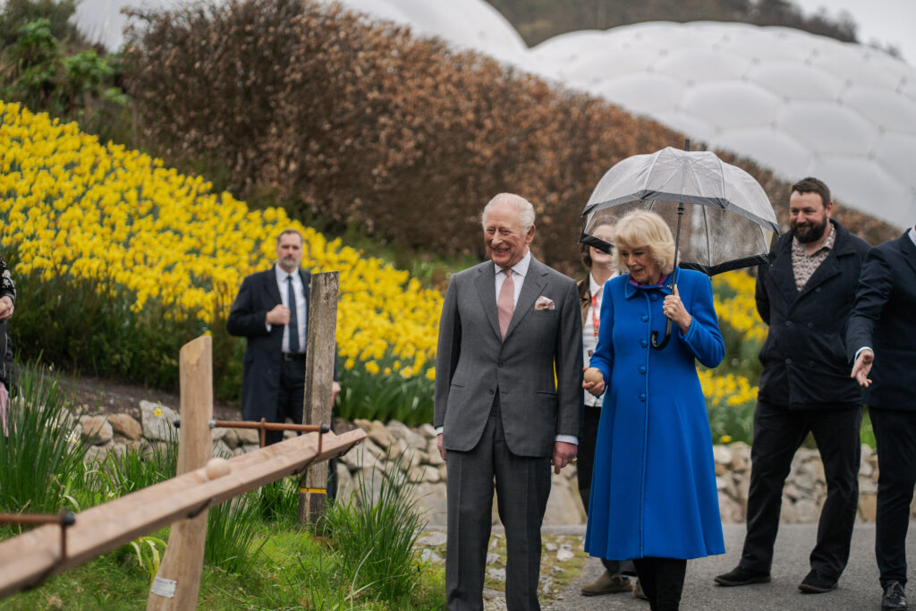 King Charles and Queen Camilla walk through the Eden Project, passing a bank of yellow flowers