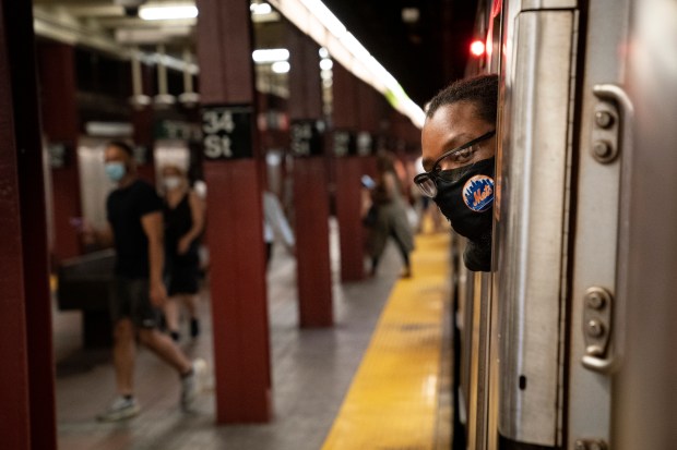 MTA subway conductor Desmond Hil looks out his crew cab window to check the platform for late-arriving passengers on the N subway line in this file photo. (John Minchillo/AP)
