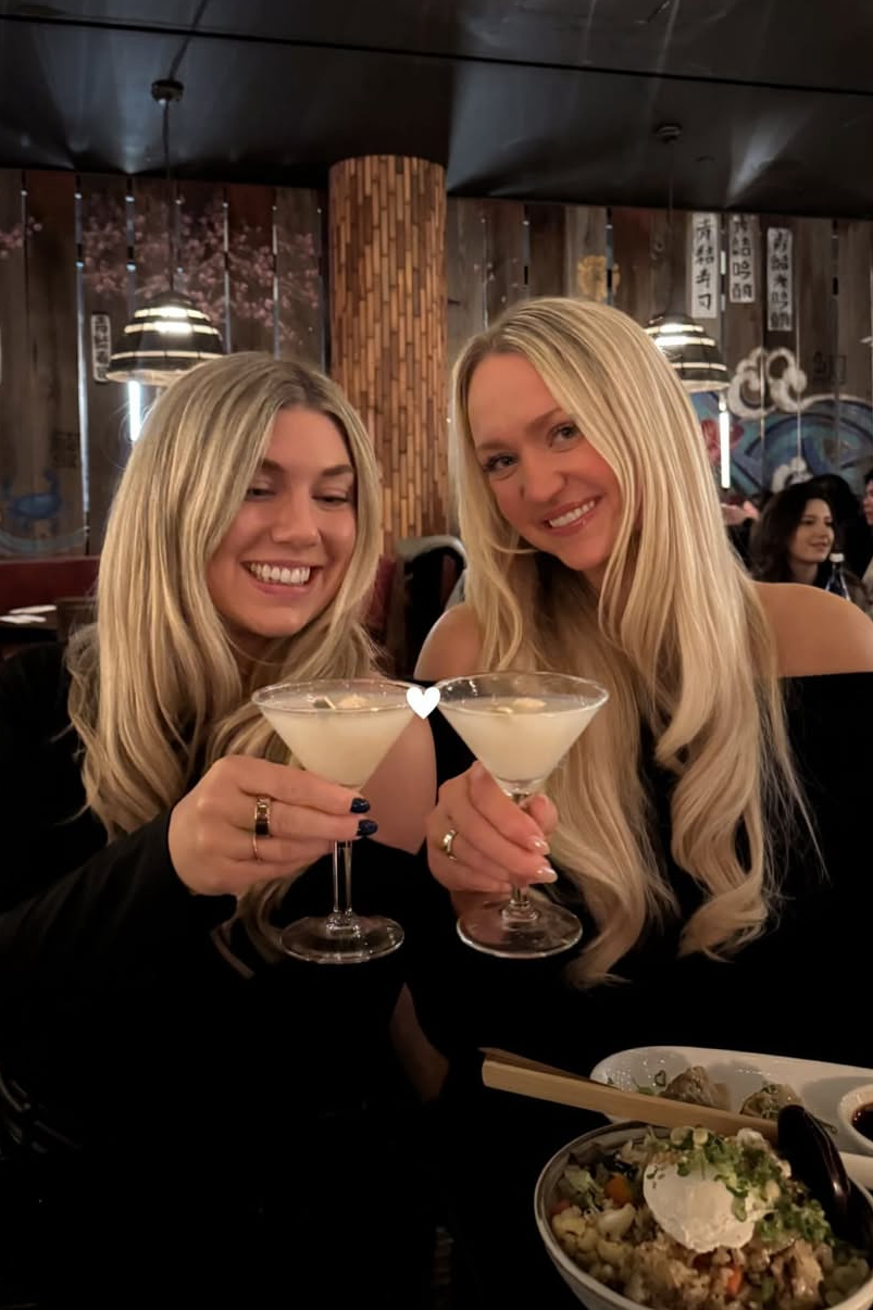 Two women toasting with cocktails at a restaurant.