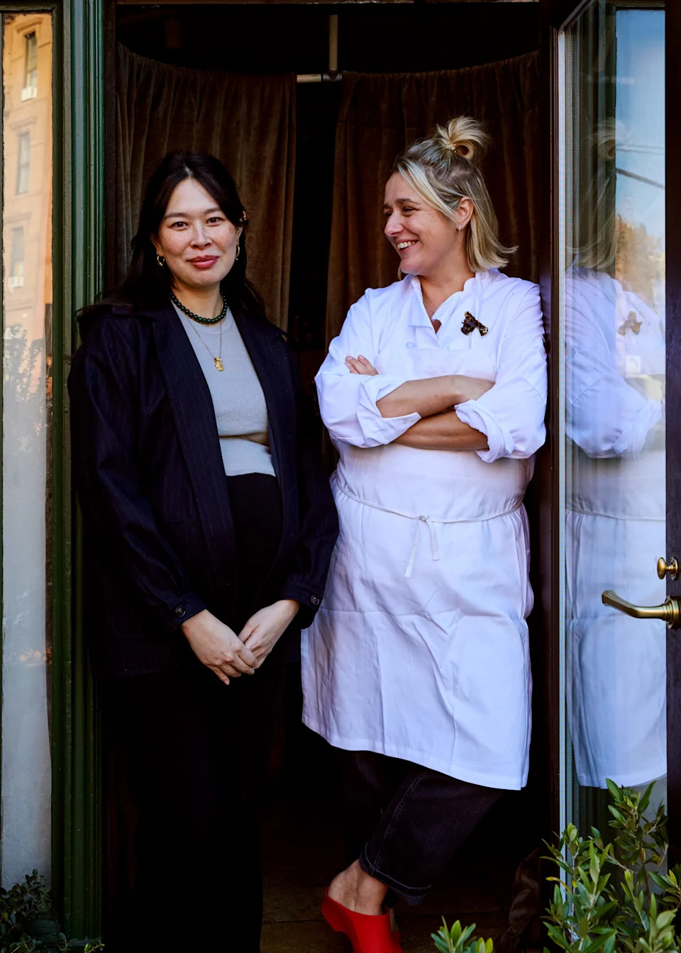 Two people standing at a restaurant door.