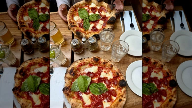 aerial shot of a restaurant table with two wood-fired Neapolitan-style pepperoni pizzas at Lil' Frankie's in New York City