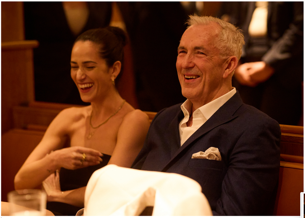 Two people seated in a formal setting, engaged in conversation. Two people seated in a formal setting, engaged in conversation.