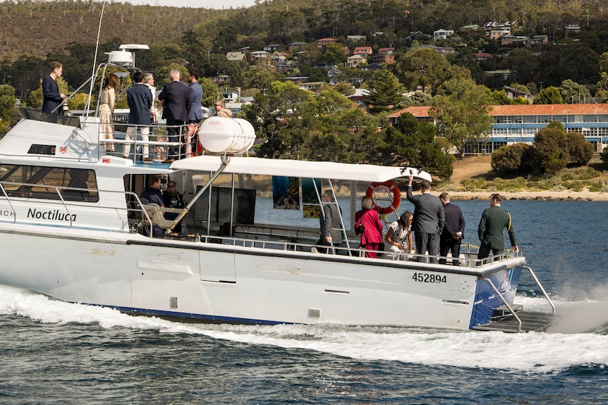 Queen Mary and others on a boat deck look out over 
