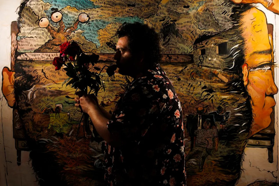 A man stands in shadow in front of a canvas.