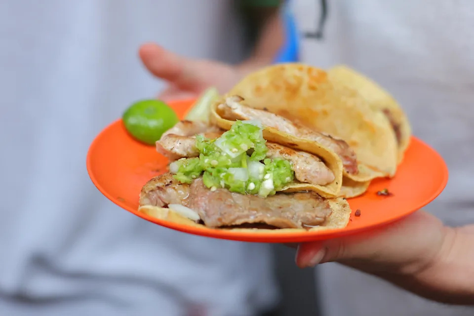 Tacos on an orange plate.