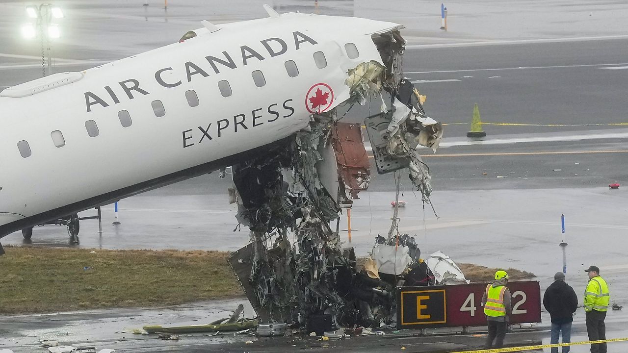 Officials investigate the site, Monday, March 23, 2026, where an Air Canada jet came to rest after colliding with a Port Authority firetruck at LaGuardia Airport, shortly after landing Sunday night in New York. (AP Photo/Seth Wenig)