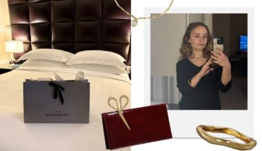 photo of alexis bittar shopping bag on a bed; mirror selfie of author wearing gold jewelry from alexis bittar, overlaid with a bangle, necklace, and merlot-colored clutch