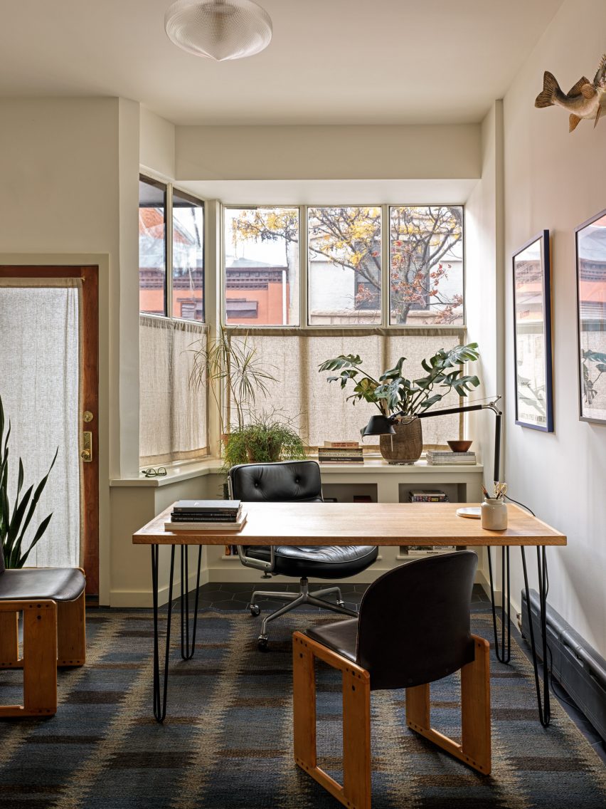 Office with storefront windows screened by cafe curtains and plants
