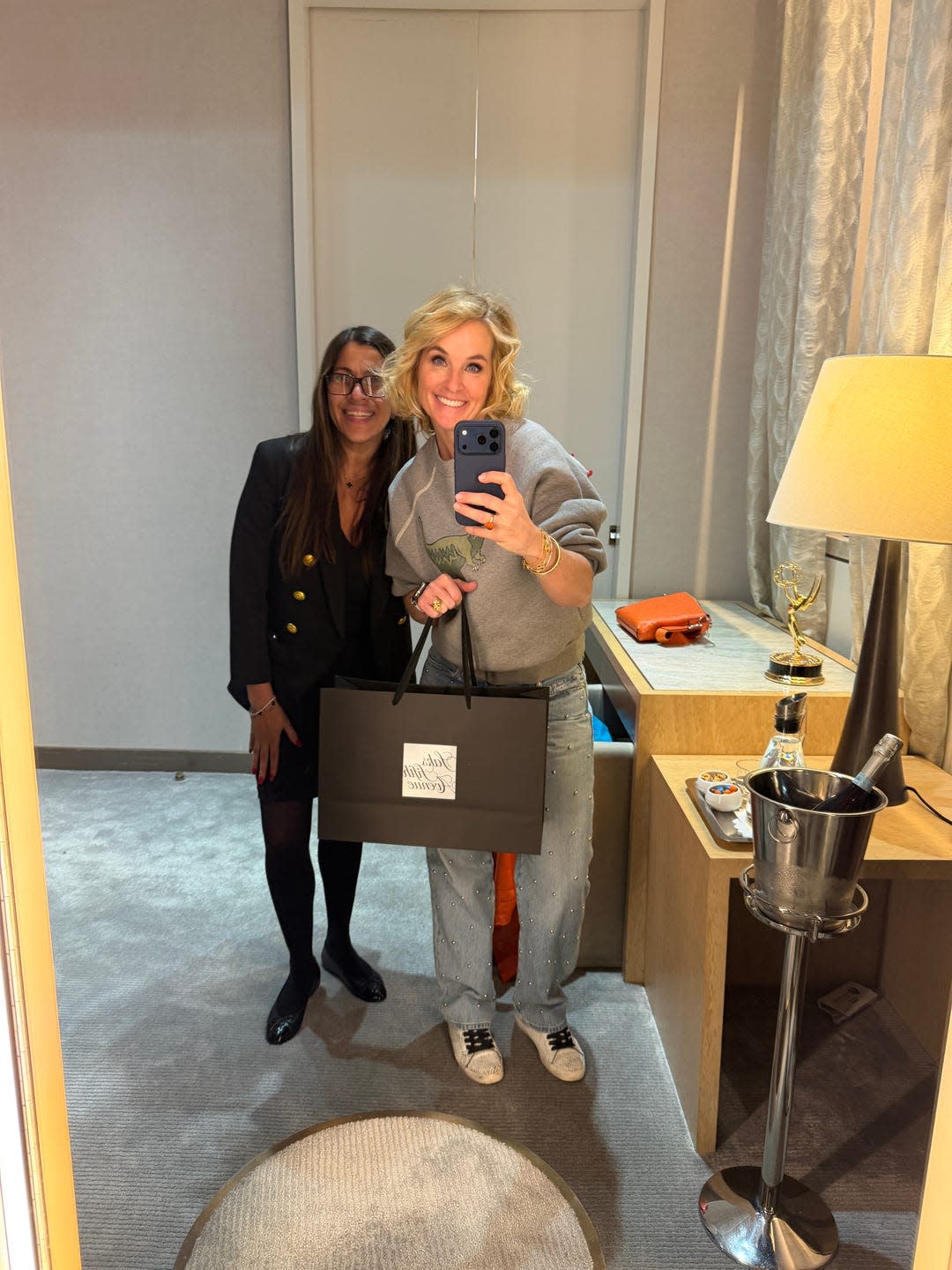 two individuals posing together in a mirror reflection one holding a shopping bag